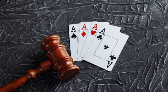 Vorteile legales Online Gluecksspiel_Richterlicher Hammer neben Spielkarten auf grauen Hintergrund